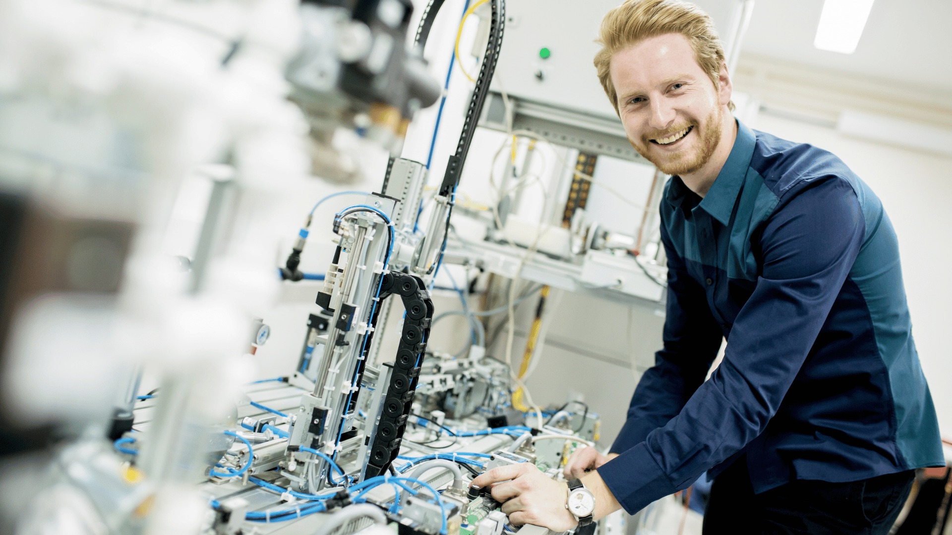 Ein freundlich lächelnder Ingenieur arbeitet an einer komplexen Industrieanlage.