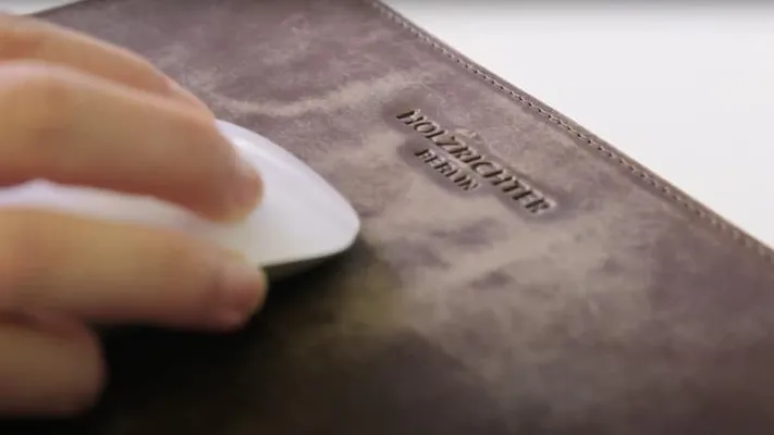 Nahaufnahme des braunen Leder-Mousepads von Holzrichter Berlin, auf dem eine Hand eine weiße Maus bewegt.