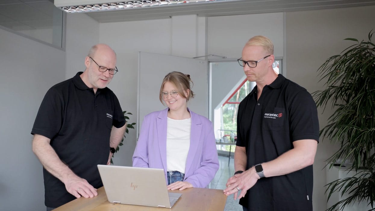Zwei Marantec-Mitarbeitende besprechen mit einer Seibert-Mitarbeiterin an einem Laptop ein Projekt in einem modernen Büro.