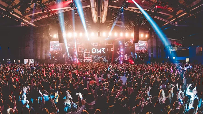 Tausende Besucher des OMR Festivals feiern in einer riesigen Halle vor einer beeindruckenden Bühne mit einer aufwendigen Lichtshow.