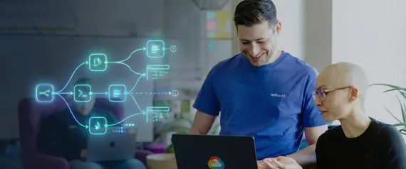 Zwei Personen arbeiten lächelnd gemeinsam an einem Laptop mit grafischen Symbolen zu Automatisierungsabläufen im Hintergrund.