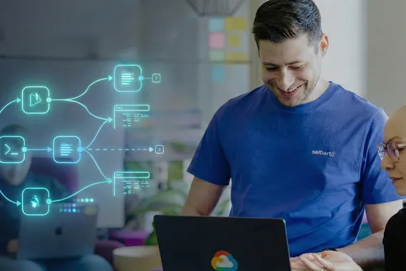 Zwei Personen arbeiten lächelnd gemeinsam an einem Laptop mit grafischen Symbolen zu Automatisierungsabläufen im Hintergrund.