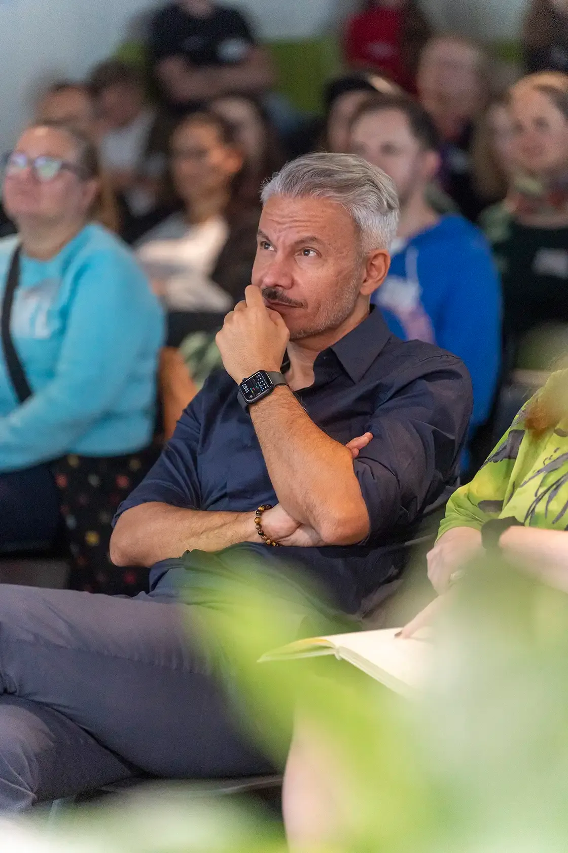 Blick in das Publikum eines Events, mit einem Mann im Fokus der gespannt zu sieht