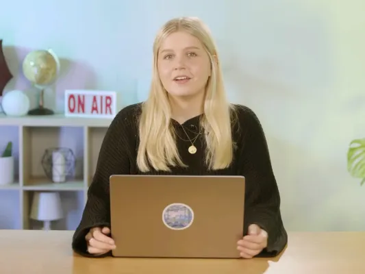 Dozentin für einen Online-Kurs über Kollaborationstools spricht in die Kamera, im Hintergrund leuchtet ein ON AIR Schild.