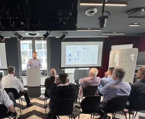 Teilnehmende eines Workshops im Google Office, vorne ein Speaker an einem Pult mit Google-Logo, im Hintergrund eine Folie zu Enterprise Architecture.