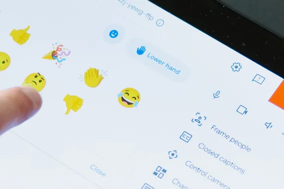 Das Touchscreenfeld der Google Meet Hardware ist zu sehen und ein Finger der auf ein Reaction Smiley klickt.