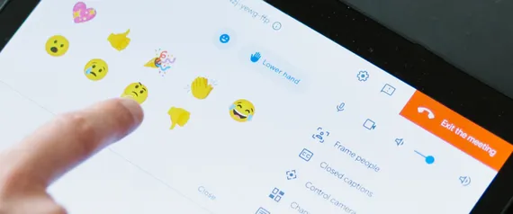 Das Touchscreenfeld der Google Meet Hardware ist zu sehen und ein Finger der auf ein Reaction Smiley klickt.